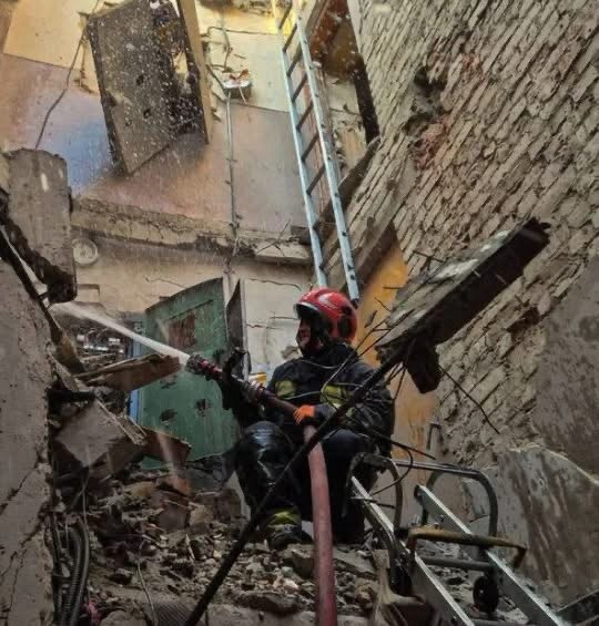 Пожежник гасить вогонь усередині будівлі, що перетворилася на руїни після удару.